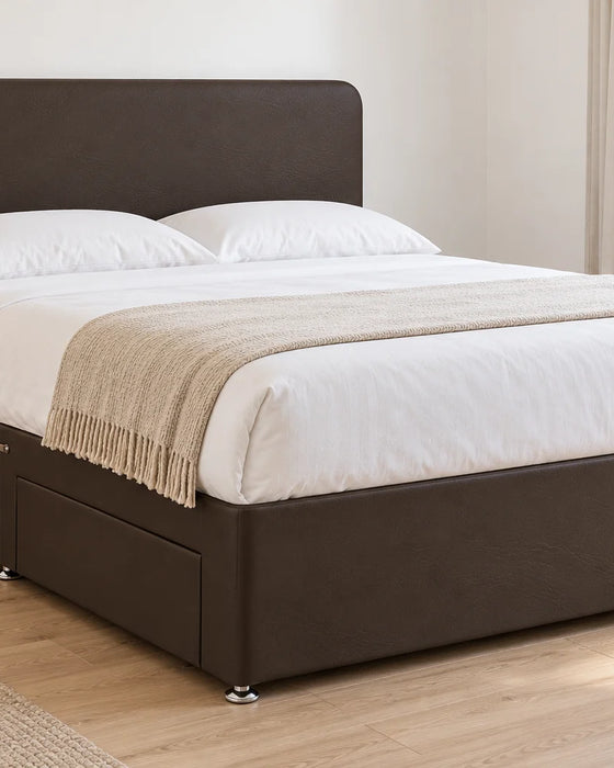 Brown faux leather divan bed base with 2 drawers and a curved headboard, in a bright UK bedroom (bedding for illustration, mattress not included)