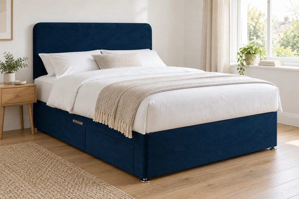 Blue velvet divan bed base with 2 drawers and a curved headboard, in a bright UK bedroom (bedding for illustration, mattress not included)