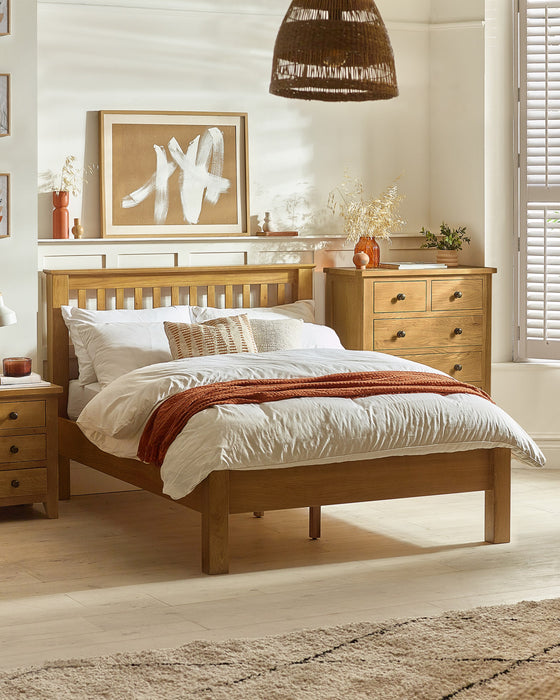Julian Bowen Amsterdam low footend bed in light oak, in a bedroom with an oak chest