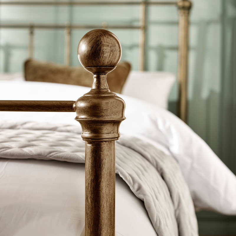 Aurelia bed: a round brass effect finial on the footboard, close up