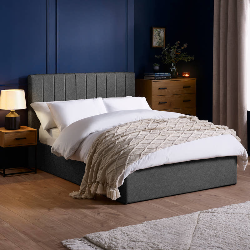 Julian Bowen Aylen ottoman bed in dark grey linen effect fabric, in a bedroom with blue walls