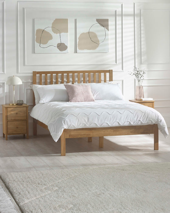 Julian Bowen Coxmoor oak bed with a tall slatted headboard, in a white panelled bedroom