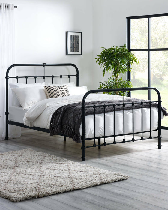 Julian Bowen Logan black metal bed with curved headboard and footboard, in a bright bedroom