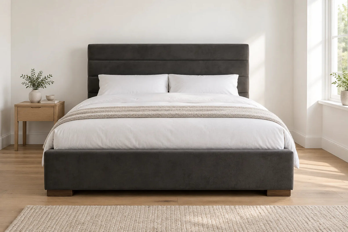 Mayfair king size ottoman bed in dark grey fabric with a channel stitched headboard, in a bright UK bedroom