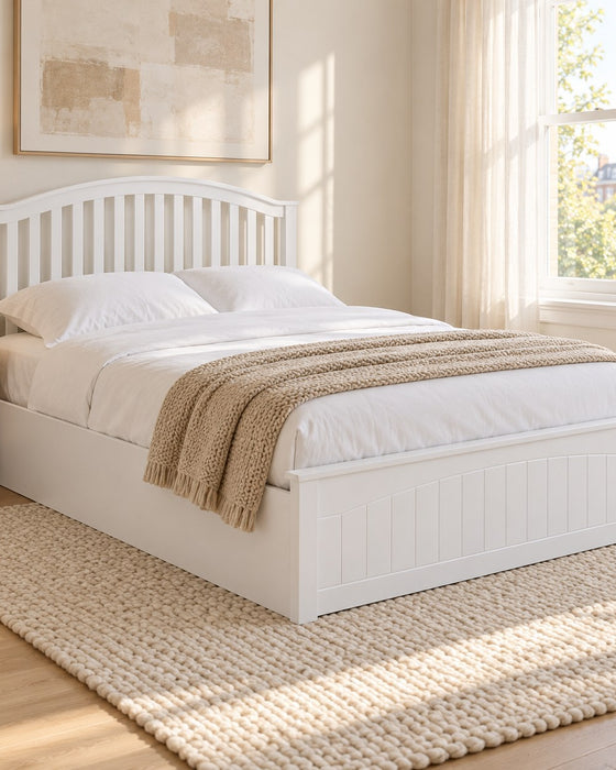 Barnet white wooden ottoman bed with a curved slatted headboard, in a bright bedroom (AI-generated illustration of this frame; bedding for illustration, mattress not included)