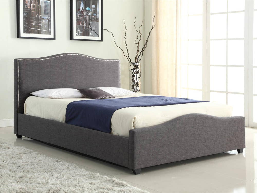 Bexley grey fabric ottoman bed with a curved studded headboard, in a bedroom