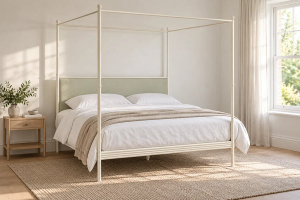 Fitzrovia ivory four poster iron bed with a sage upholstered headboard, shown in a bright UK bedroom