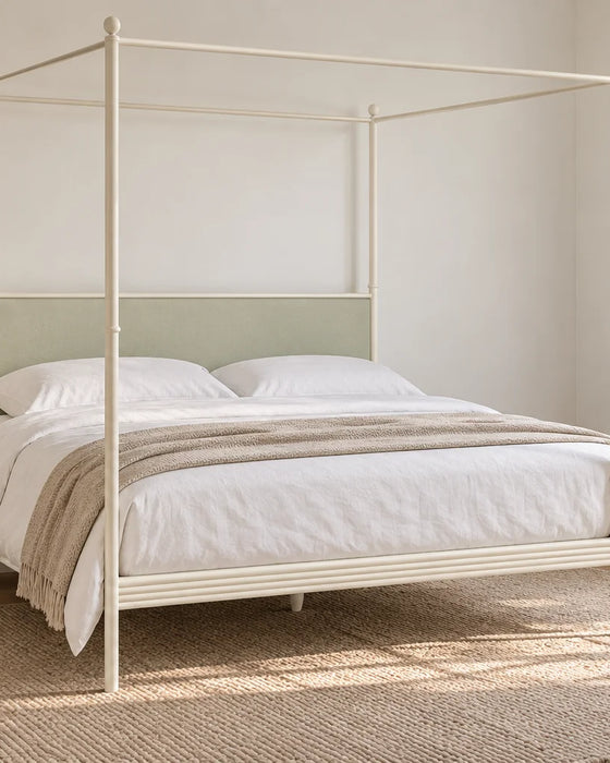 Fitzrovia ivory four poster iron bed with a sage upholstered headboard, shown in a bright UK bedroom