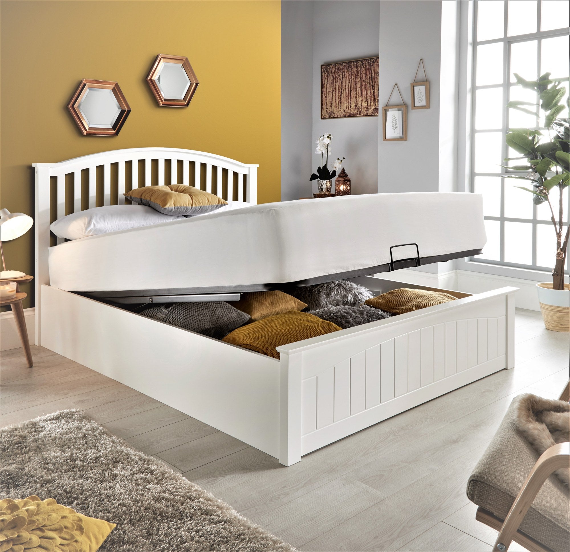 Barnet wooden ottoman bed in white, with the storage open, in a bedroom