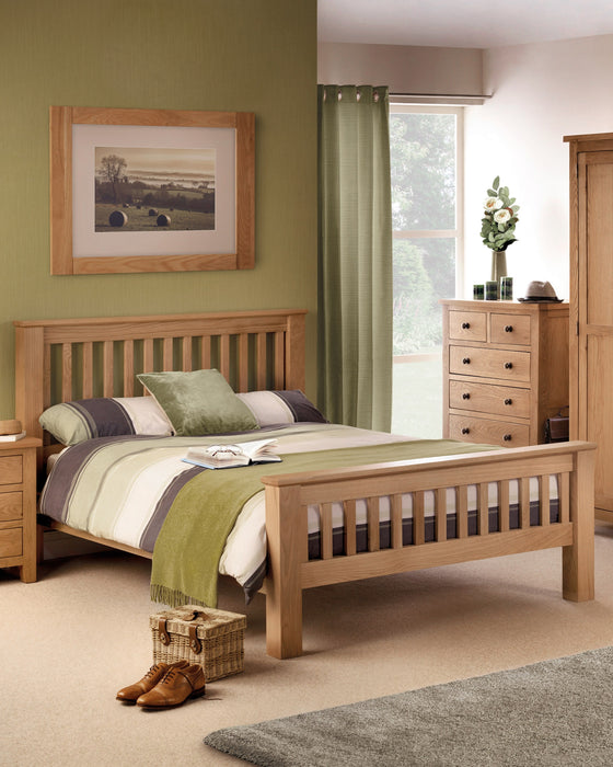 Julian Bowen Amsterdam oak bed with a high slatted footend, in a bedroom with a green wall