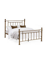 Julian Bowen Aurelia brass effect metal bed made up with bedding, on a white background