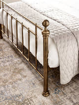 Aurelia bed: the brass effect footboard post and bars, close up