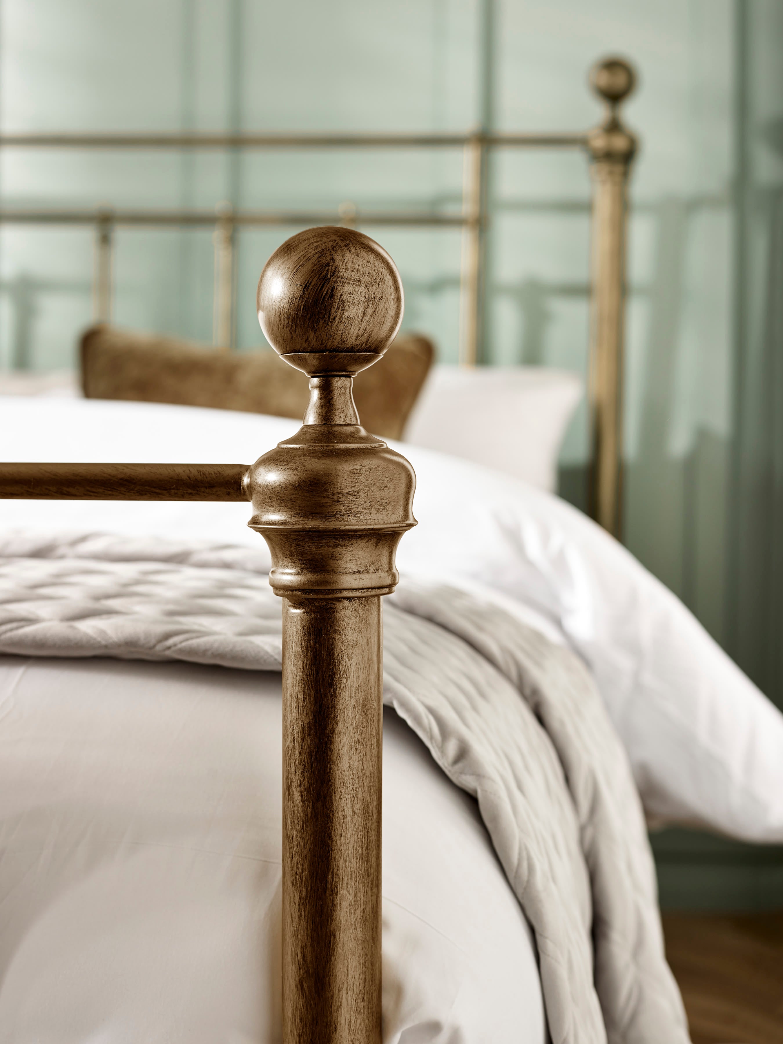 Aurelia bed: a round brass effect finial on the footboard, close up