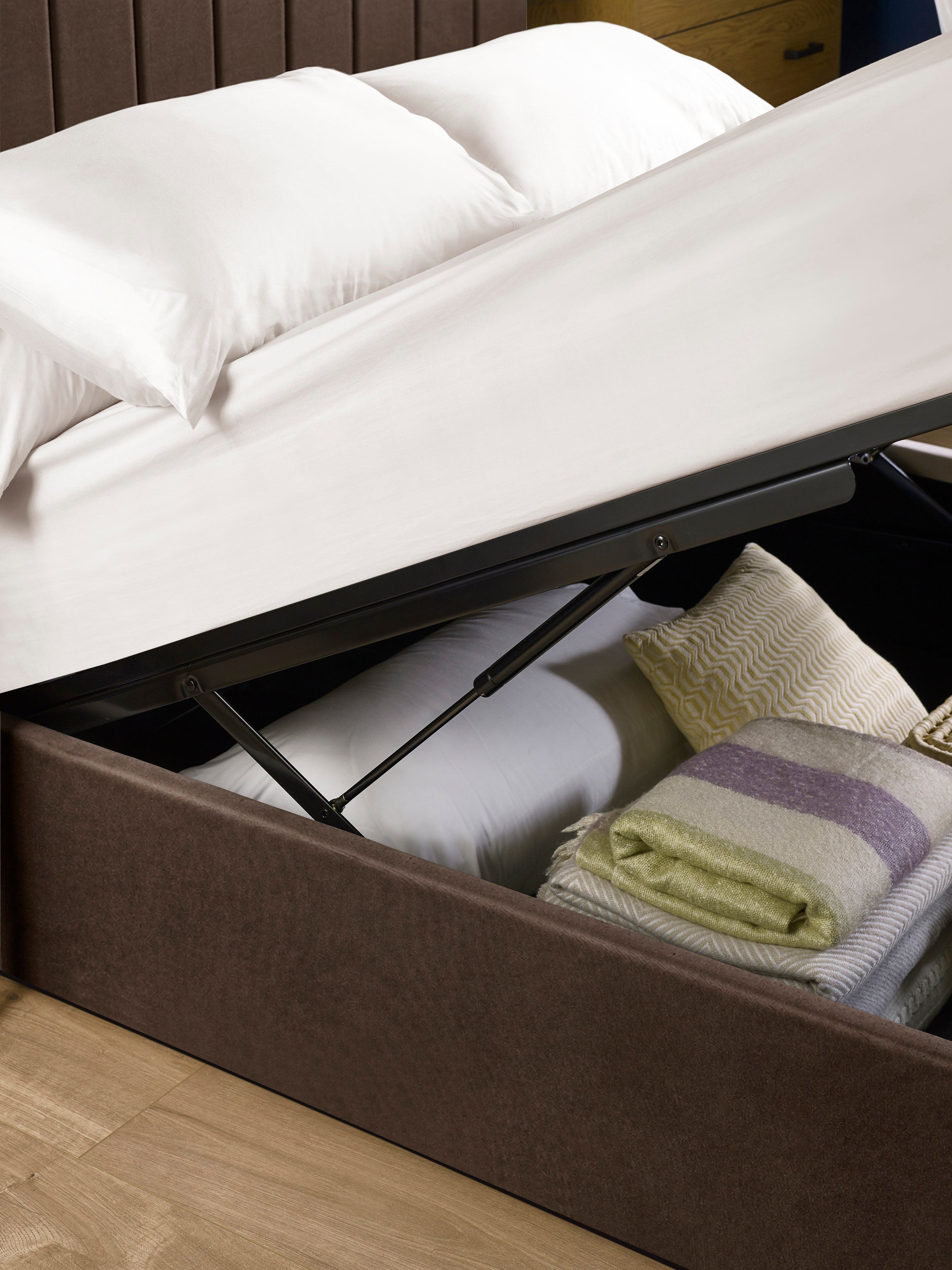 Aylen ottoman bed: gas lift raising the base over folded blankets, close up