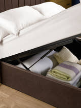 Aylen ottoman bed: gas lift raising the base over folded blankets, close up