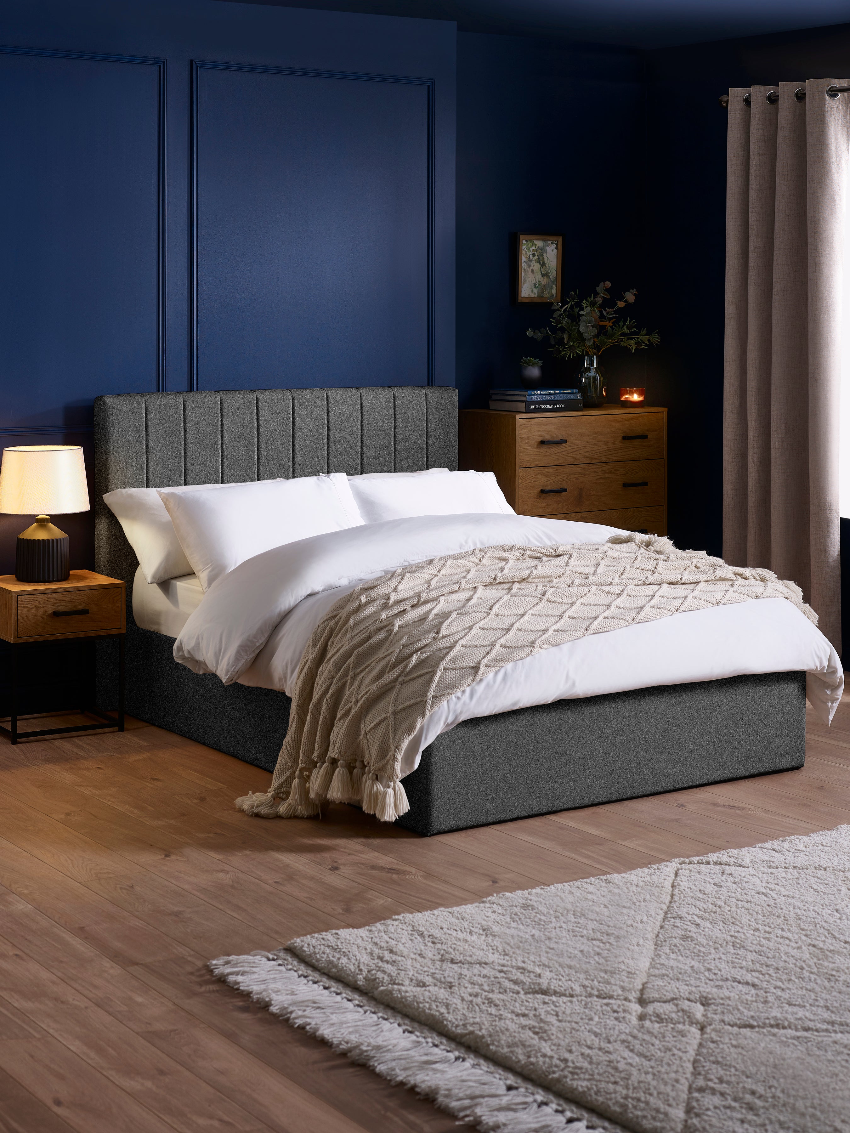 Julian Bowen Aylen ottoman bed in dark grey linen effect fabric, in a bedroom with blue walls