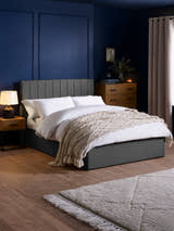 Julian Bowen Aylen ottoman bed in dark grey linen effect fabric, in a bedroom with blue walls