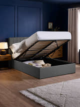 Aylen dark grey ottoman bed with the base lifted to show the storage, in a bedroom