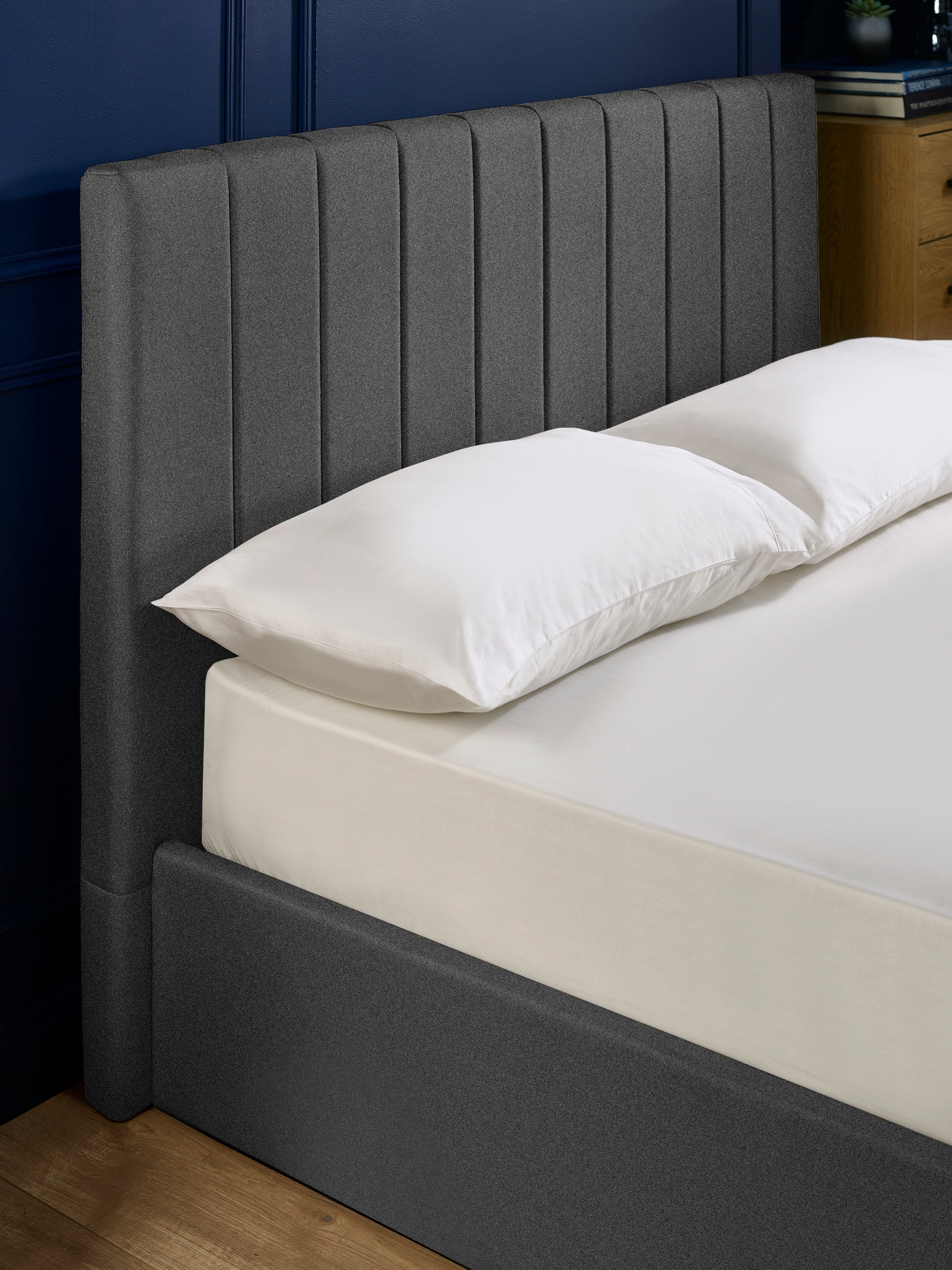 Aylen bed: dark grey headboard padded in vertical channels, close up