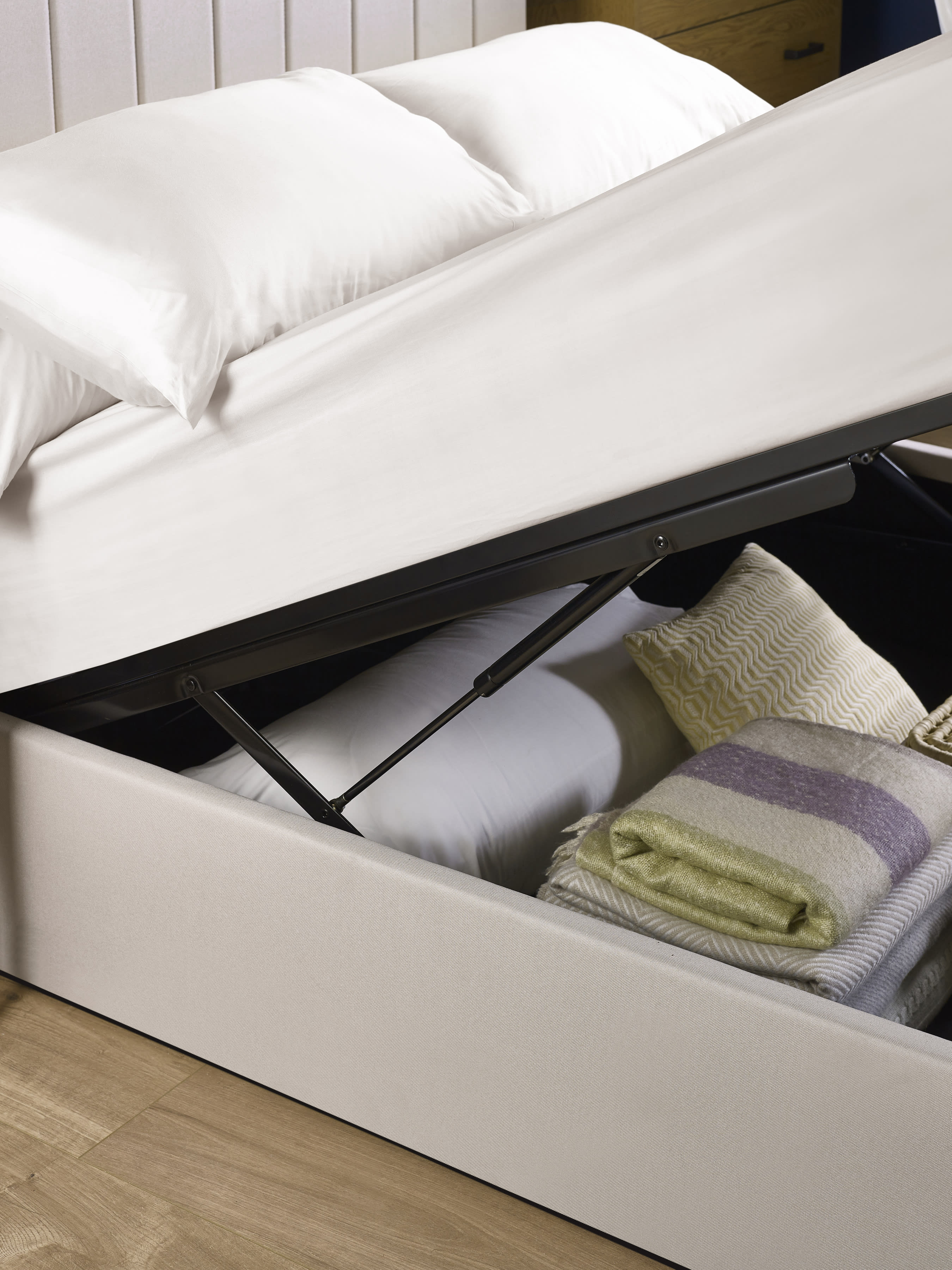 Aylen ottoman bed: gas lift raising the oatmeal base over folded blankets, close up