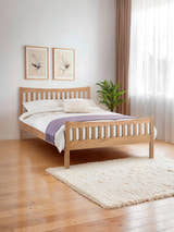 Julian Bowen Bergamo solid oak bed with a slatted headboard and footboard, in a bright bedroom