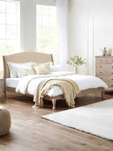 Julian Bowen Camille limed oak bed with curved oatmeal linen headboard, in a bright bedroom