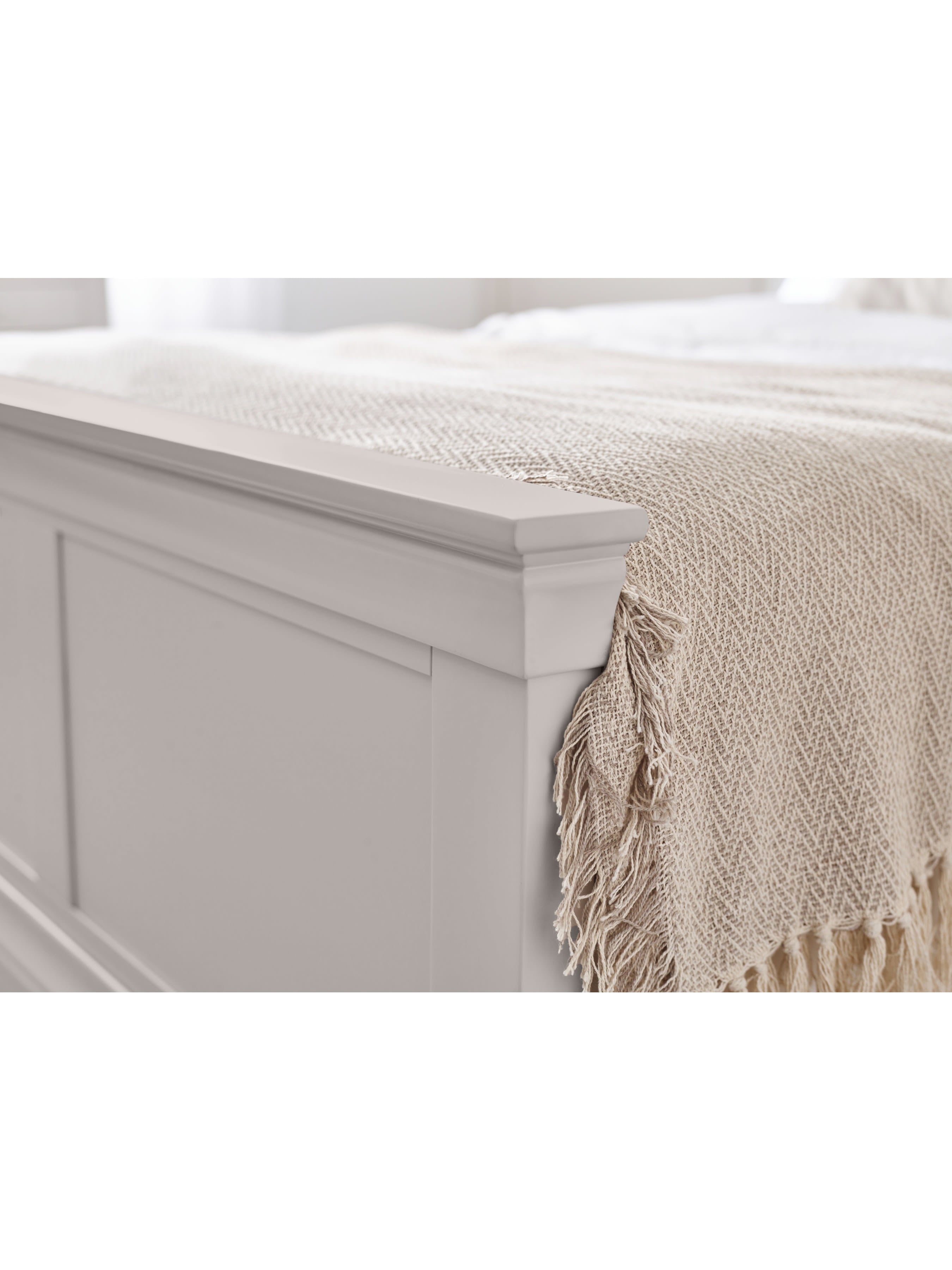 Clermont bed: the light grey panelled footboard with a throw, close up