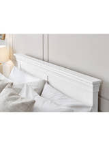 Clermont bed: the surf white headboard with its tapered cornice, behind pillows