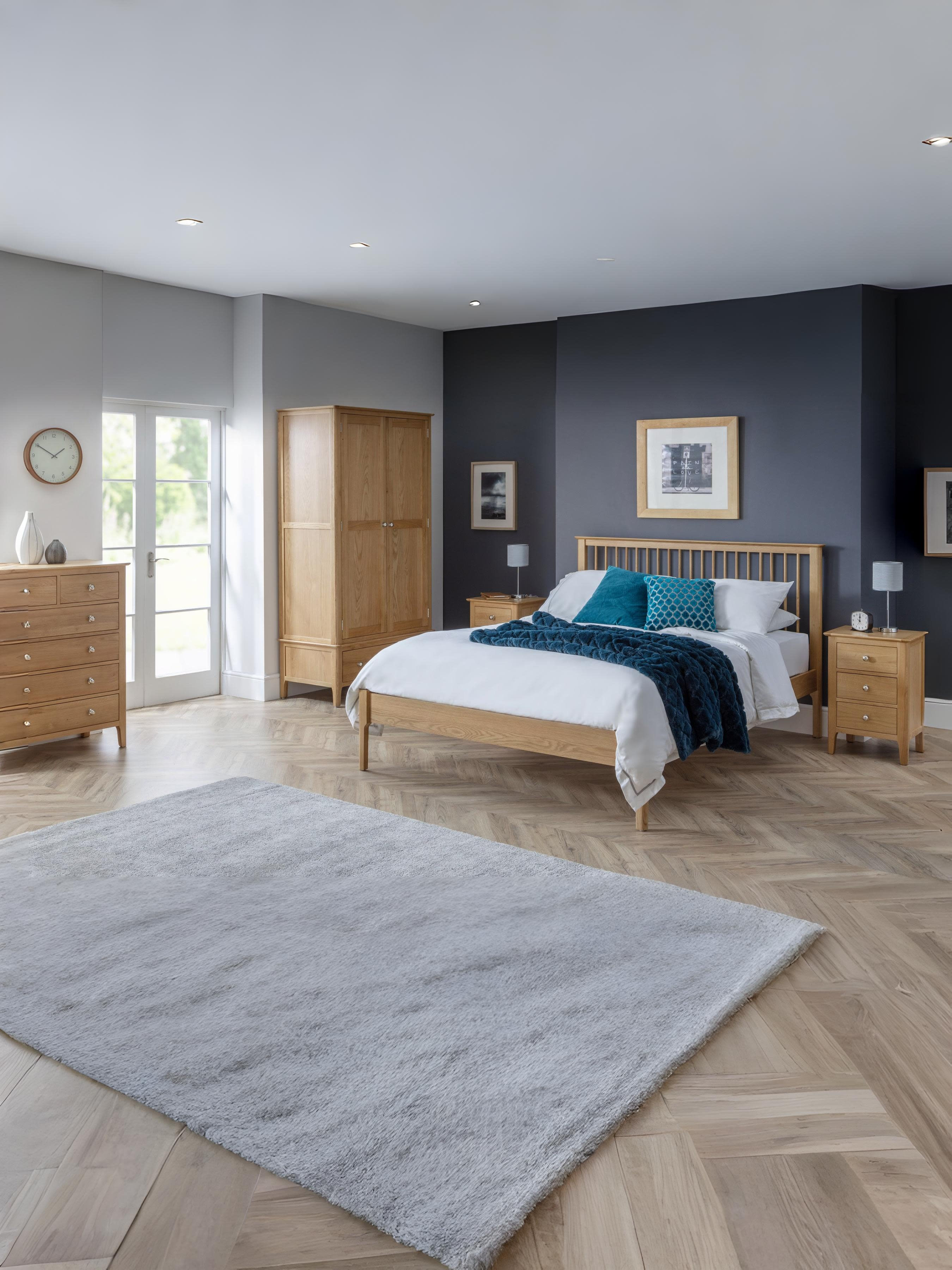 Julian Bowen Cotswold oak bed in a large bedroom with matching oak furniture, wide view