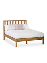 Julian Bowen Coxmoor oak bed made up with white bedding, on a white background