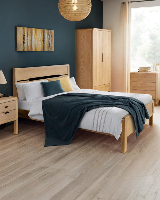 Julian Bowen Curve oak bed with a cut-out headboard, in a bedroom with a dark blue wall