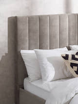Eloise bed: tall grey chenille headboard behind white pillows, close up