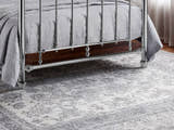Julian Bowen Empress chrome bed: lower footboard rail and feet on a grey rug, close up