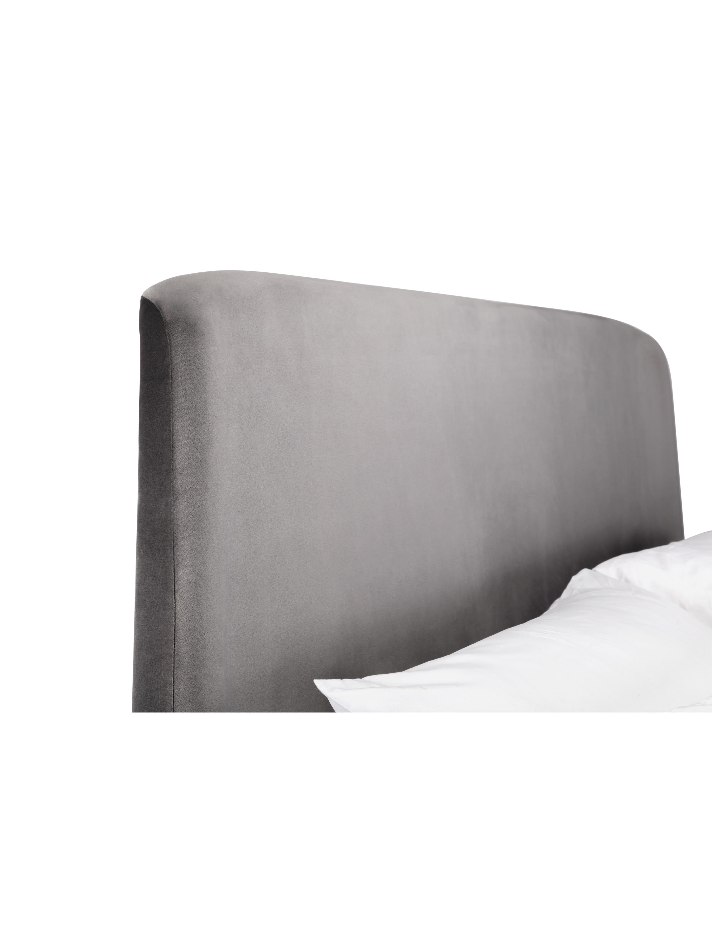 Frida bed: curved grey velvet headboard behind a pillow, close up