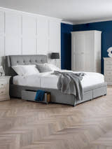 Julian Bowen Fullerton grey linen bed with a buttoned headboard and a drawer open, in a bedroom