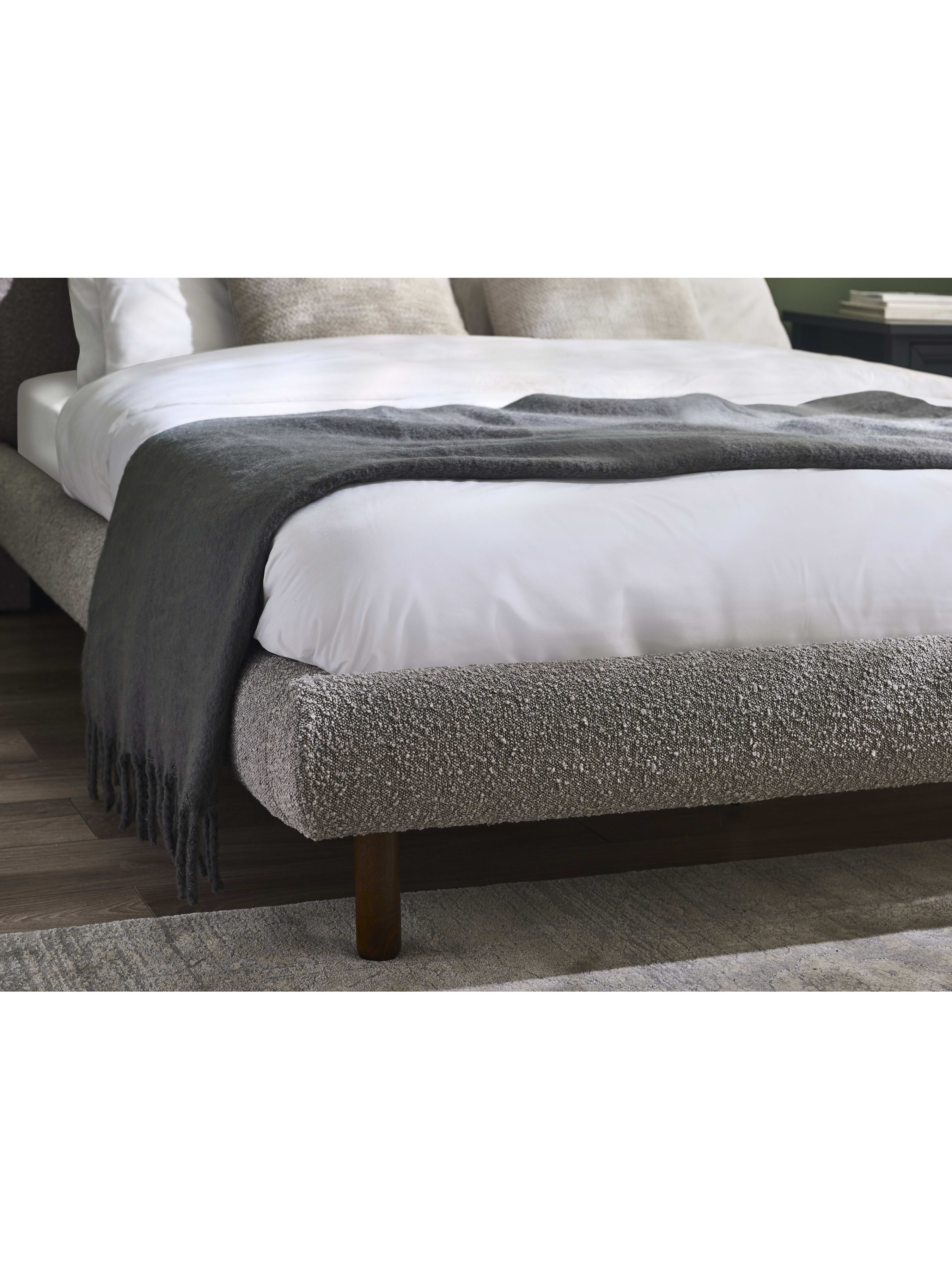 Hannah bed: the rounded grey boucle foot end with a throw, in a bedroom