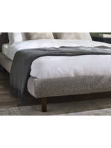 Hannah bed: the rounded grey boucle foot end with a throw, in a bedroom