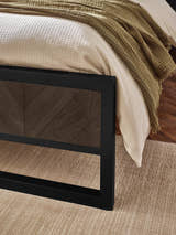 Harrison bed: black metal footboard with a herringbone effect panel, close up