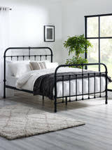 Julian Bowen Logan black metal bed with curved headboard and footboard, in a bright bedroom