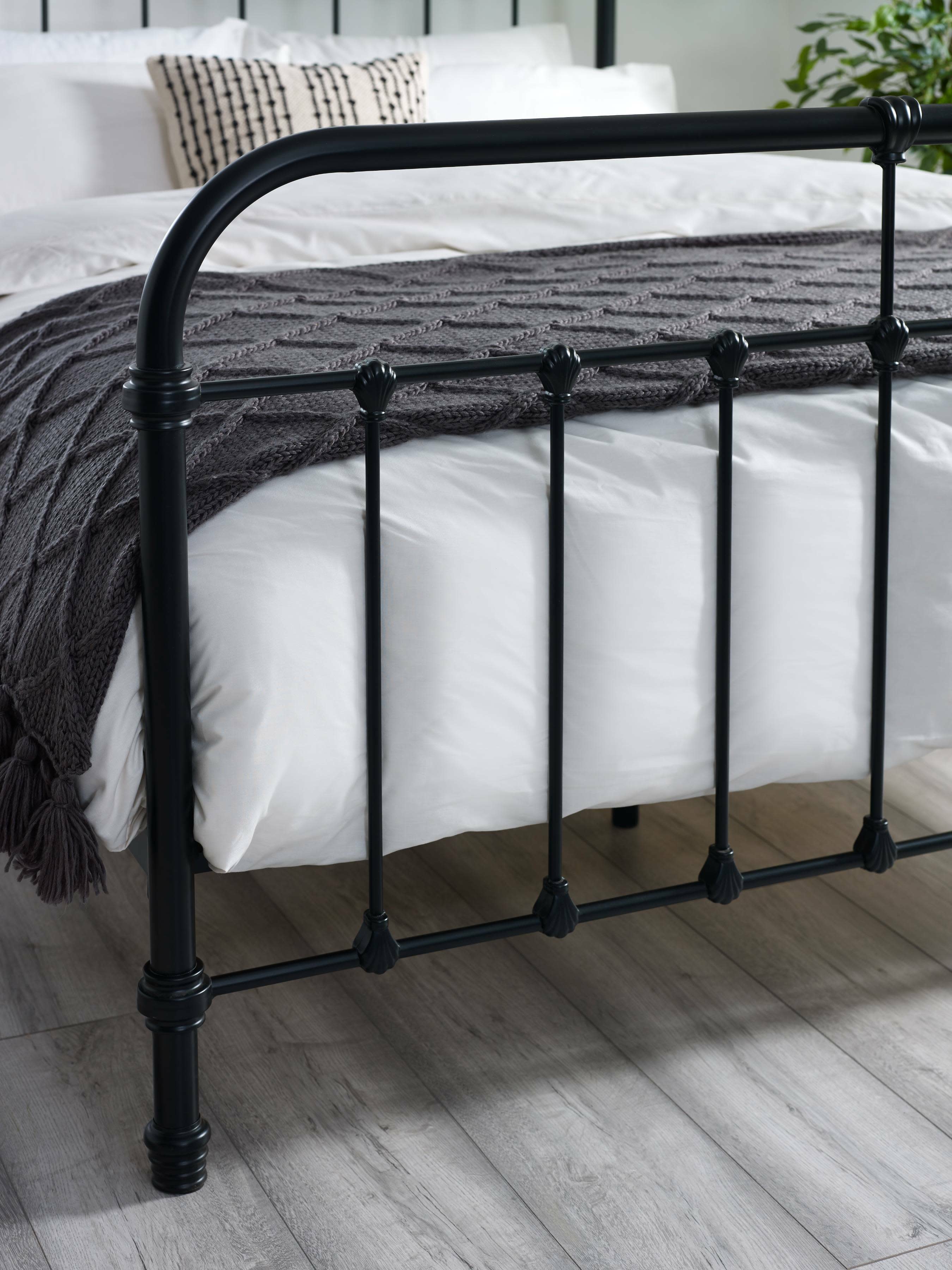 Logan bed: the black footboard with its curved rail and cast details, close up