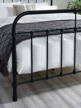 Logan bed: the black footboard with its curved rail and cast details, close up