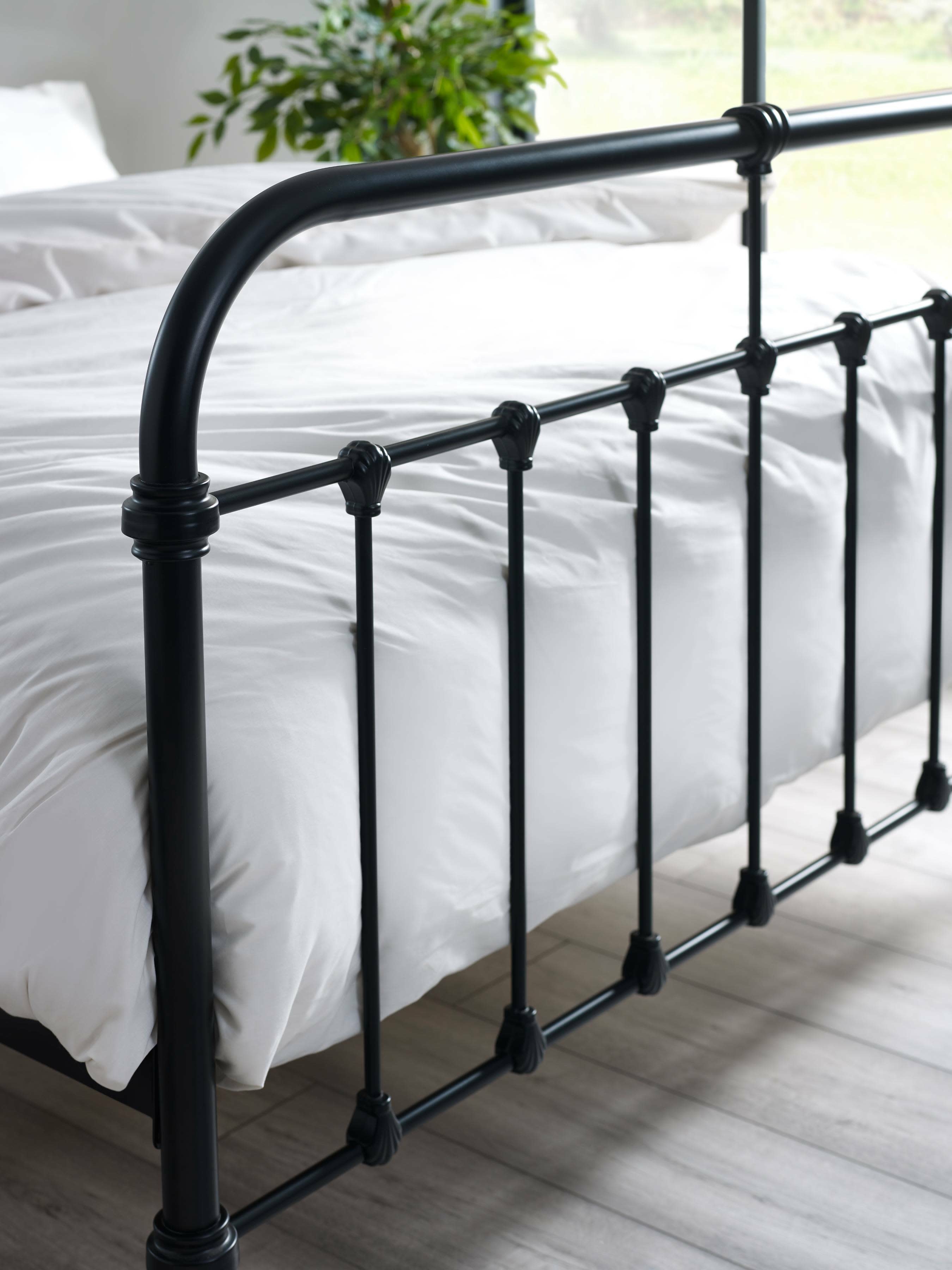Logan bed: the black footboard rails over white bedding, close up