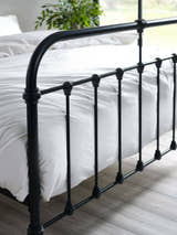 Logan bed: the black footboard rails over white bedding, close up