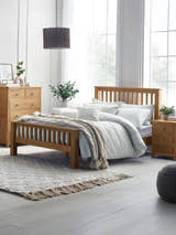 Julian Bowen Mallory oak bed with a high slatted footend, in a bright bedroom