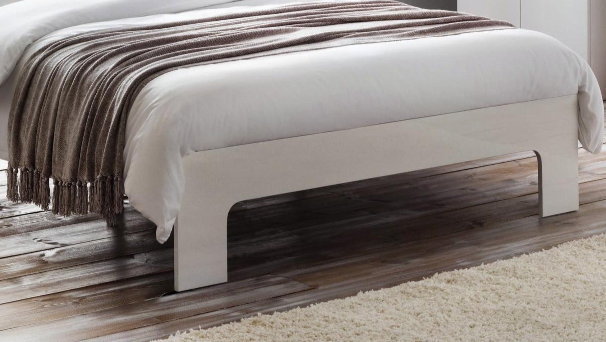 Julian Bowen Manhattan white high gloss footend and block legs on a wooden floor, close up