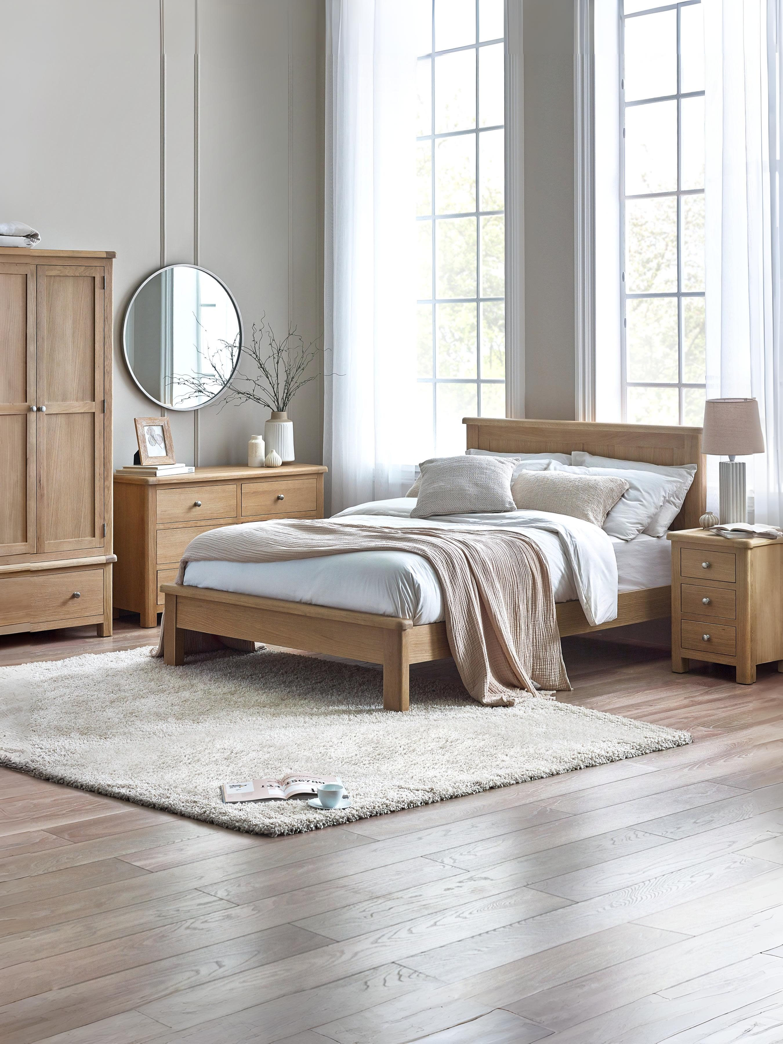 Julian Bowen Memphis limed oak bed in a large bedroom with matching furniture, wide view