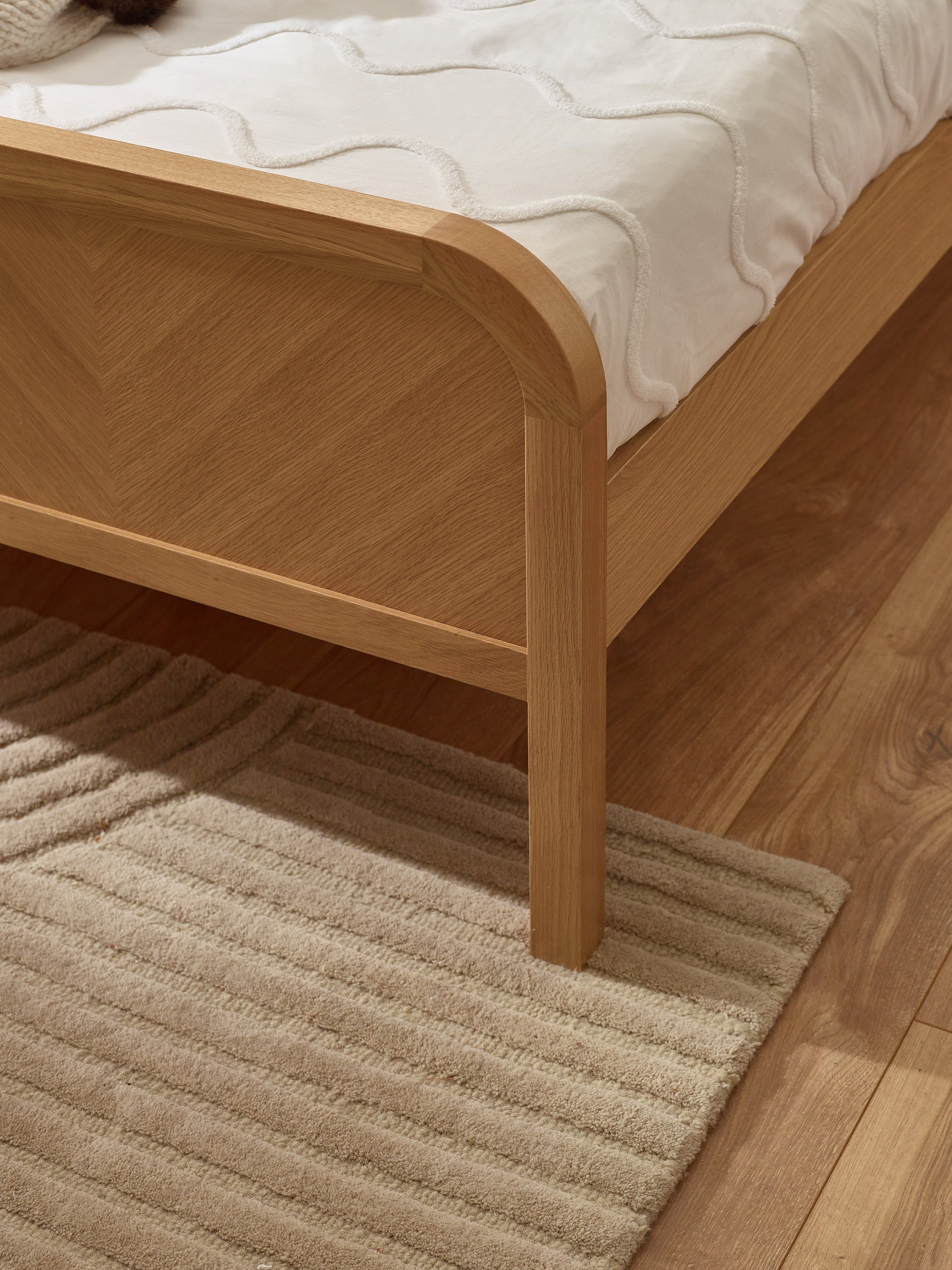 Milo bed: the chevron footboard and rounded oak border, close up