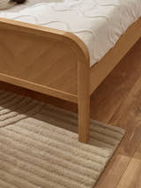 Milo bed: the chevron footboard and rounded oak border, close up