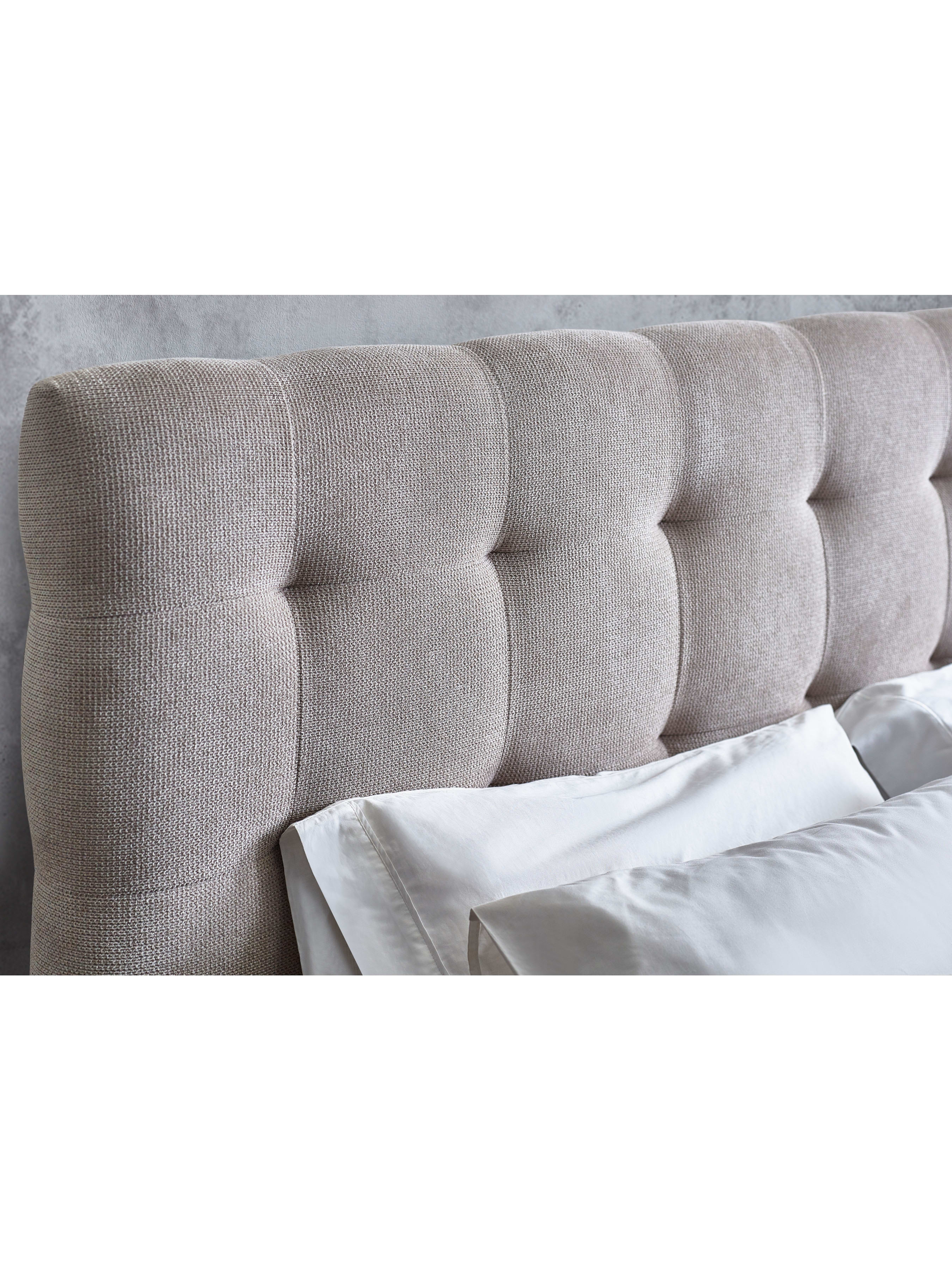 Odette bed: tall buttoned headboard behind white pillows, close up