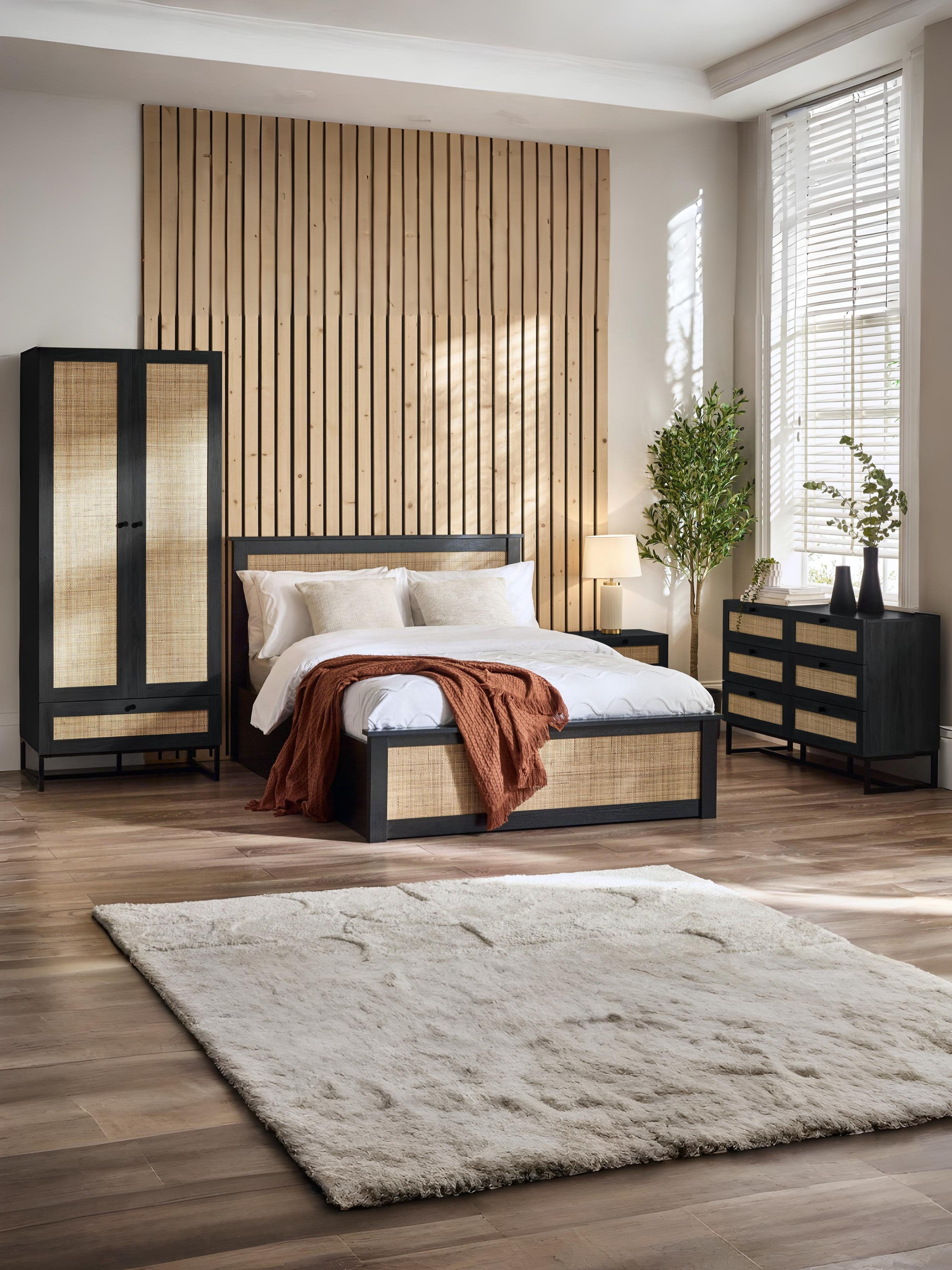 Julian Bowen Padstow black rattan ottoman bed in a large bedroom, wide view